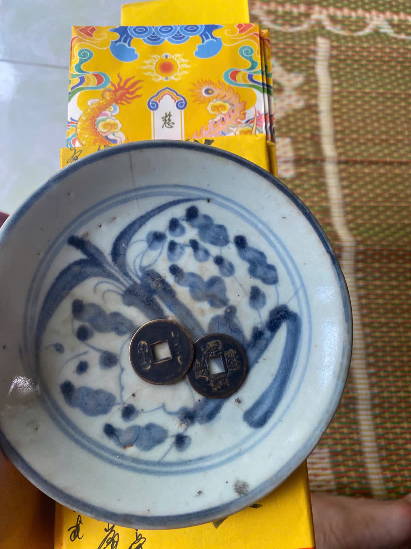 2 đồng tiền cổ đặt trên chiếc đĩa sứ men lam cổ để gieo quẻ xin keo âm dương trong lễ tạ mộ