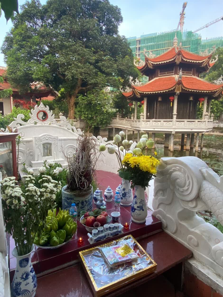 Ngôi mộ cổ của bà Tổ Cô bên hồ sen, phía sau là ngôi thủy đình gỗ mái đỏ soi bóng xuống mặt nước