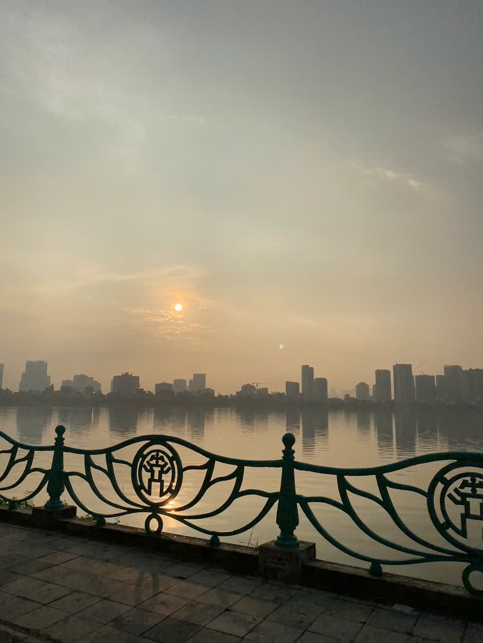 Hồ Tây buổi sớm với mặt nước phẳng lặng và đường chân trời thành phố Hà Nội trong nắng dịu